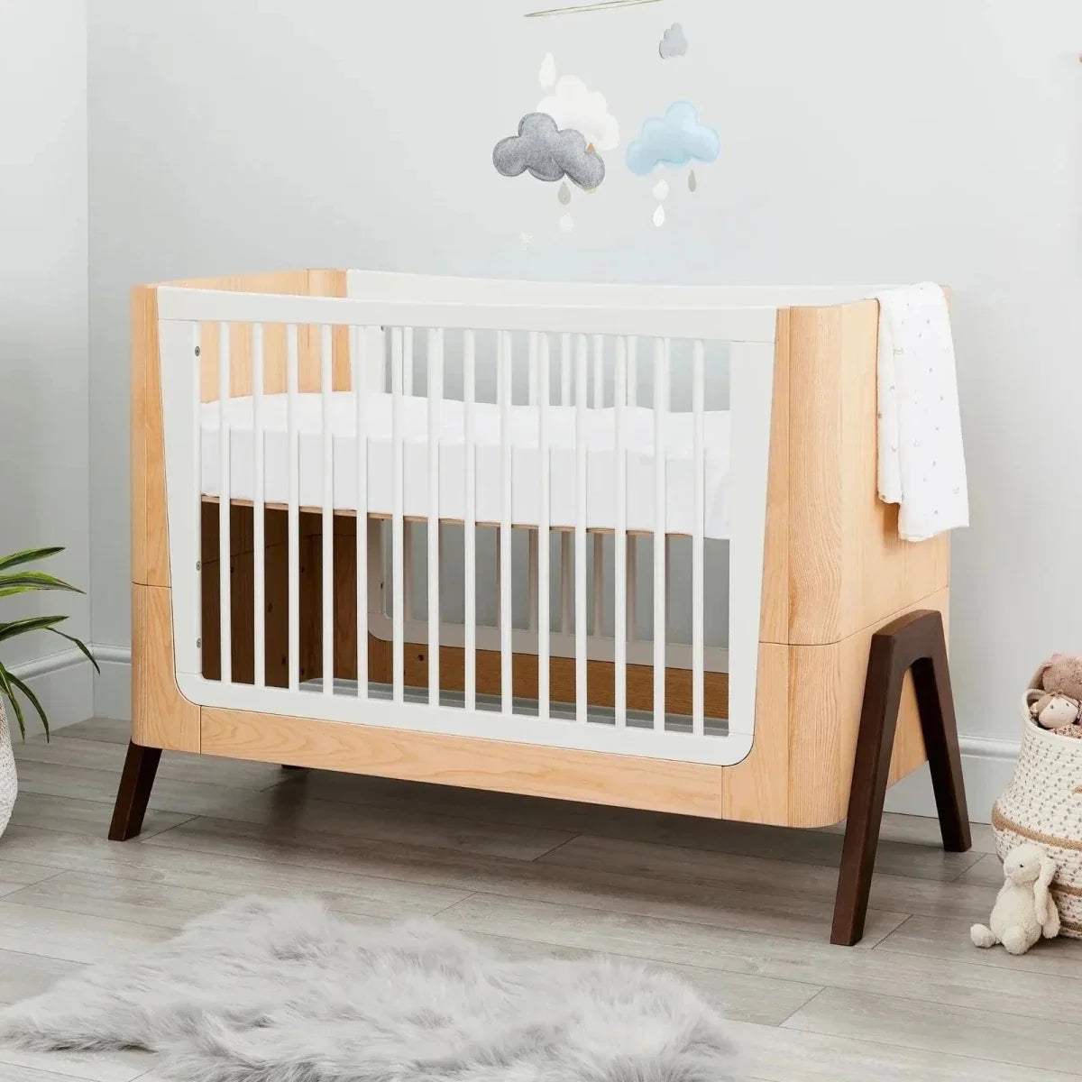 Convertible baby cot bed with natural wood frame, white slatted ends, dark tapered legs