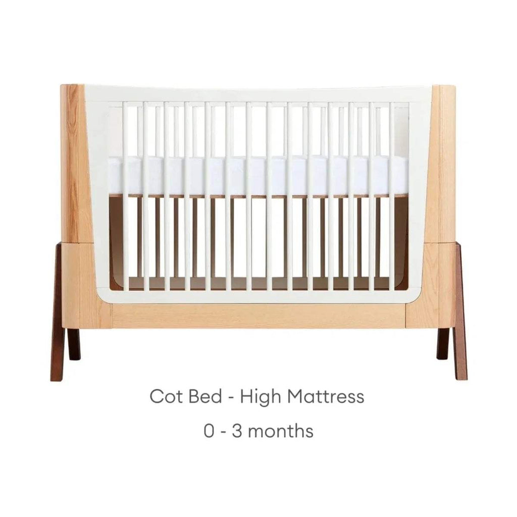 Cot bed with high mattress position; 0–3 months label, white slats and natural frame