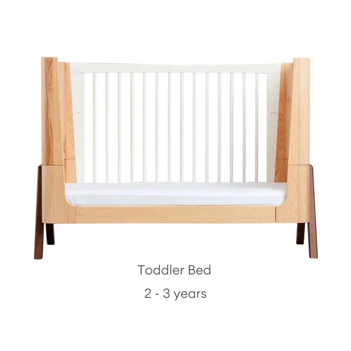 Convertible toddler bed with natural wood frame, white front panel, and slat ends