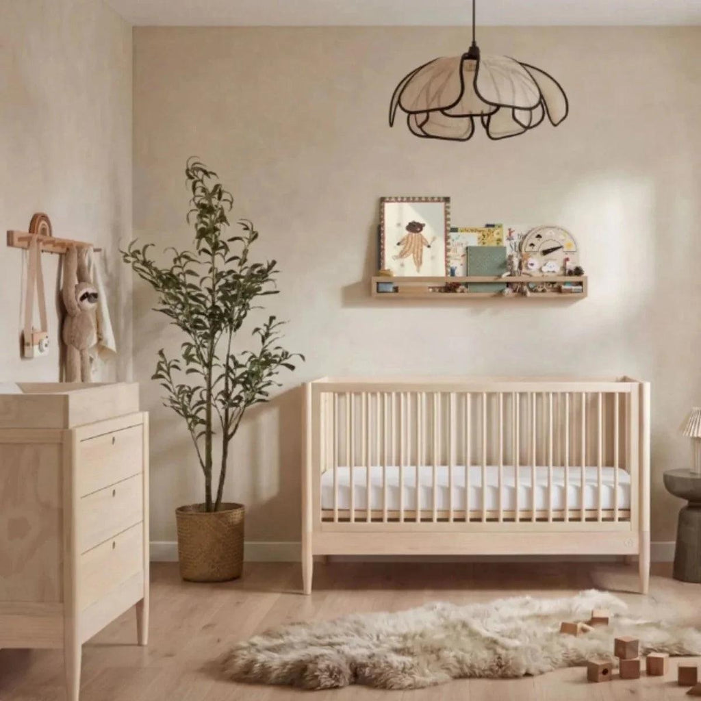 Natural ash baby crib with vertical slat sides and white mattress