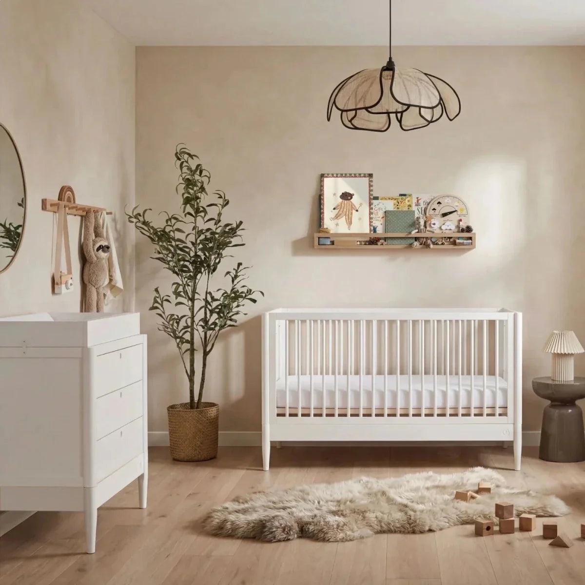 All-white nursery room set with white crib, rug, and matching white dresser