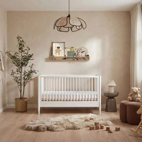 All-white nursery room set with white crib, bedside lamp, and teddy chair