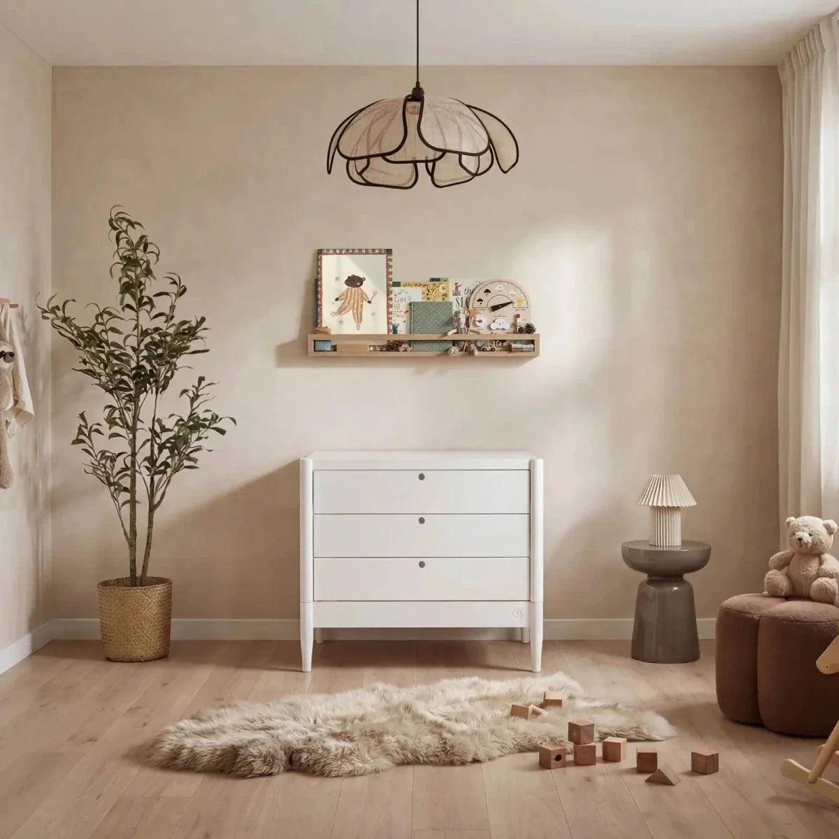 All-white nursery room set with white crib and white dresser with three drawers