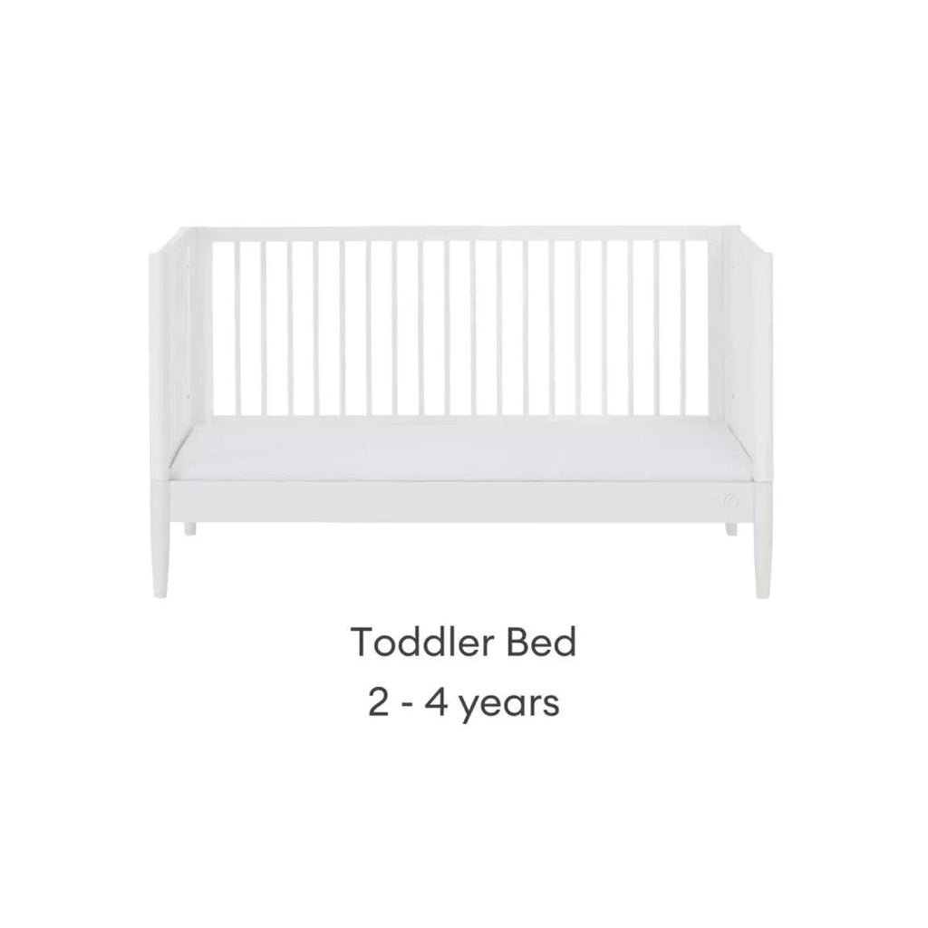 White toddler bed with low side rails and padded mattress, front view