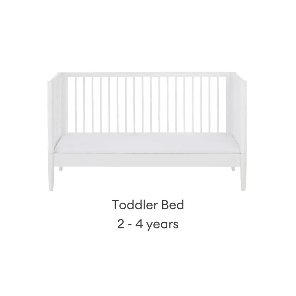 White toddler bed with low side rails and padded mattress, front view