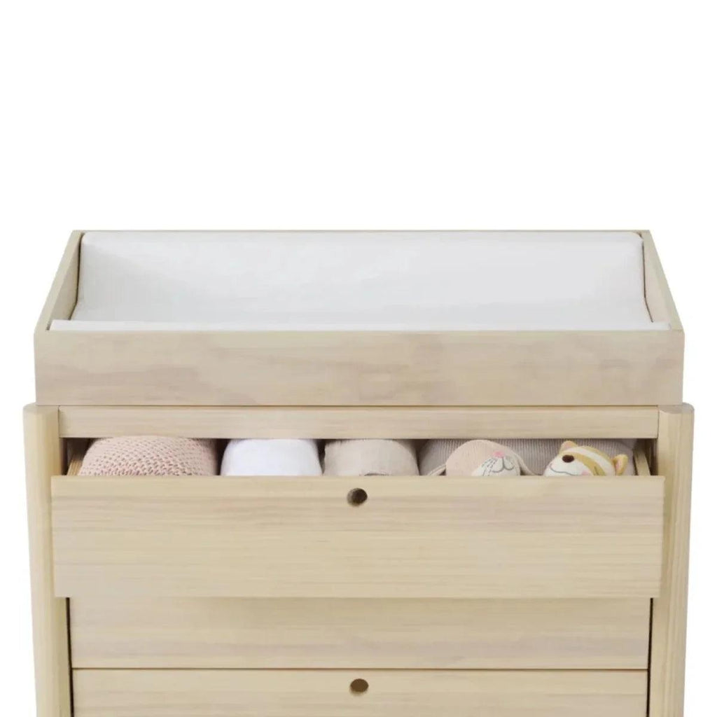 Wood crib-changing top with open drawer showing folded linens and a smooth changing surface