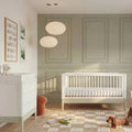 White baby crib with slatted sides from a 2-piece room set, desert sage accent rail