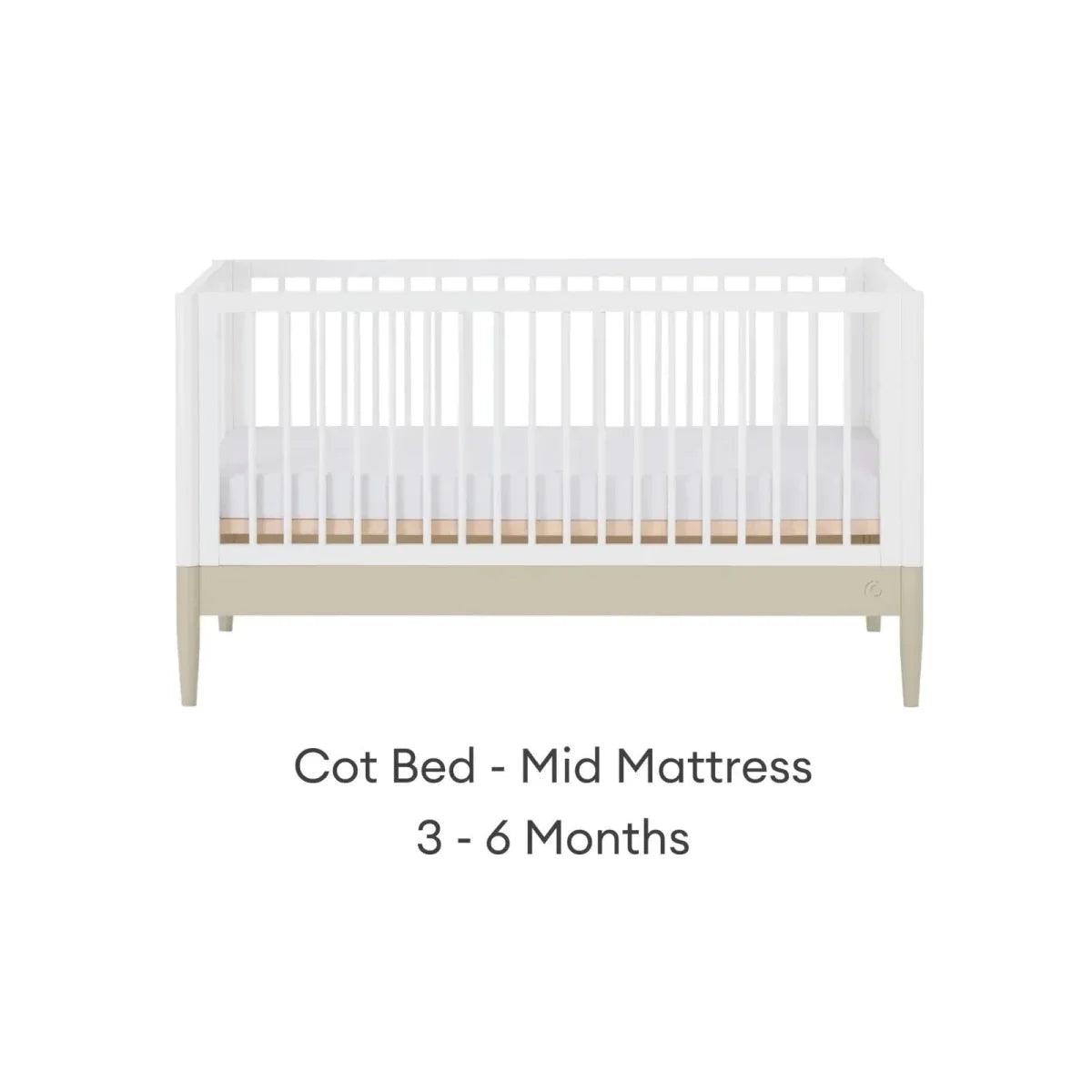 White cot bed frame with mid mattress position and light wood legs