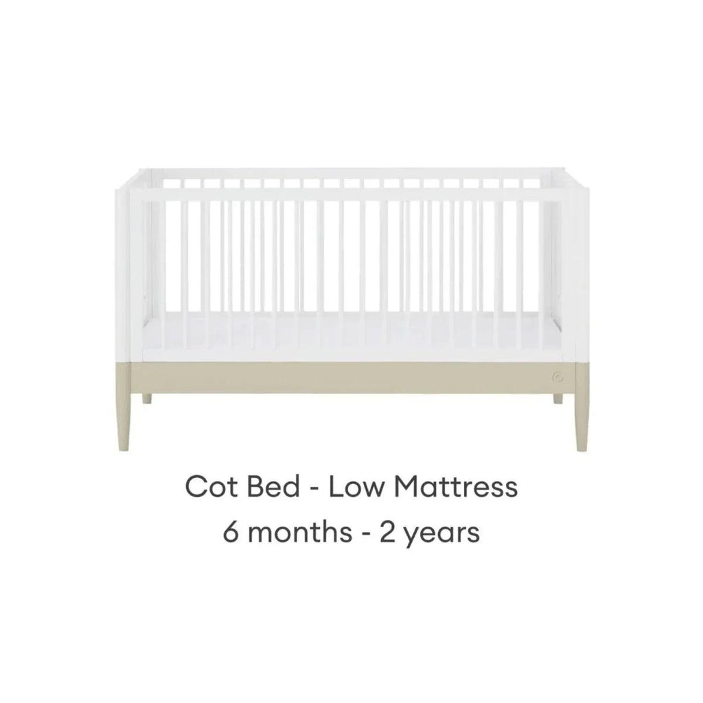 White cot bed frame with low mattress position and light wood legs