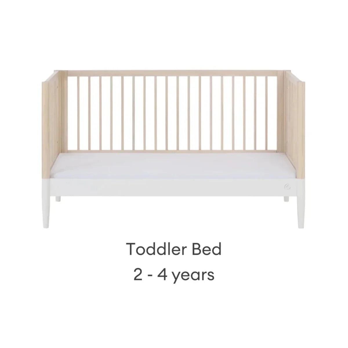 Toddler bed with natural ash frame and white mattress, low front and side rails