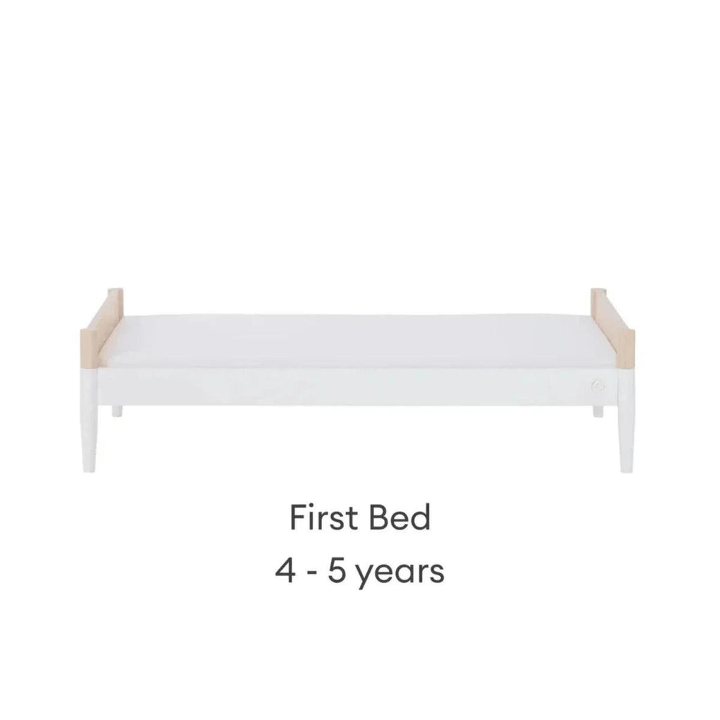 First bed with natural ash end panels and white mattress, low guard profile