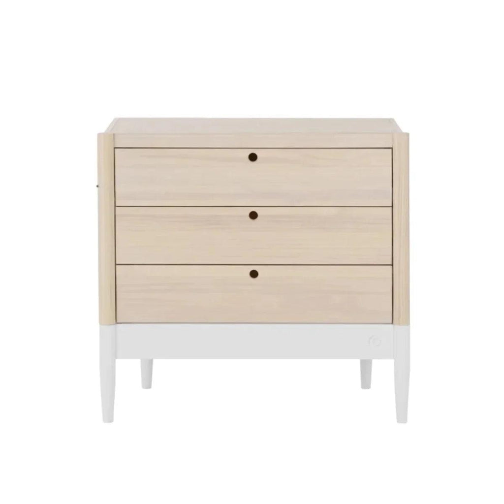 Wooden baby changing unit with three drawer fronts and centered knobs, natural ash