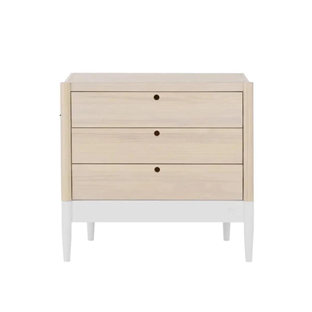 Wooden baby changing unit with three drawer fronts and centered knobs, natural ash