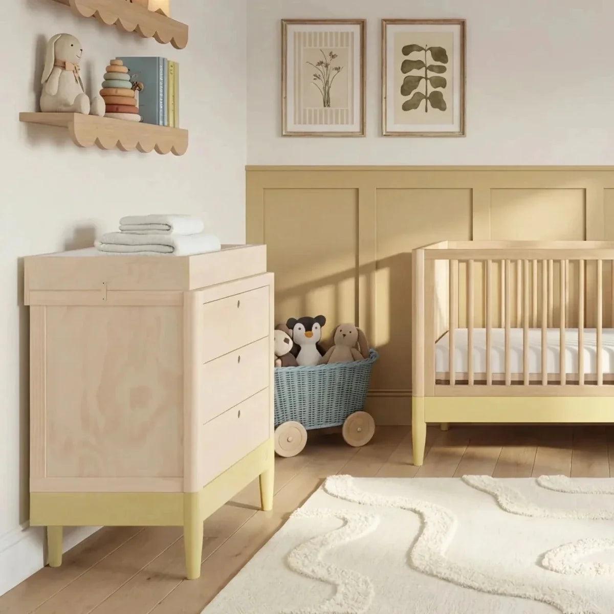 Baby room set showing light wood cot bed and white dresser with drawers