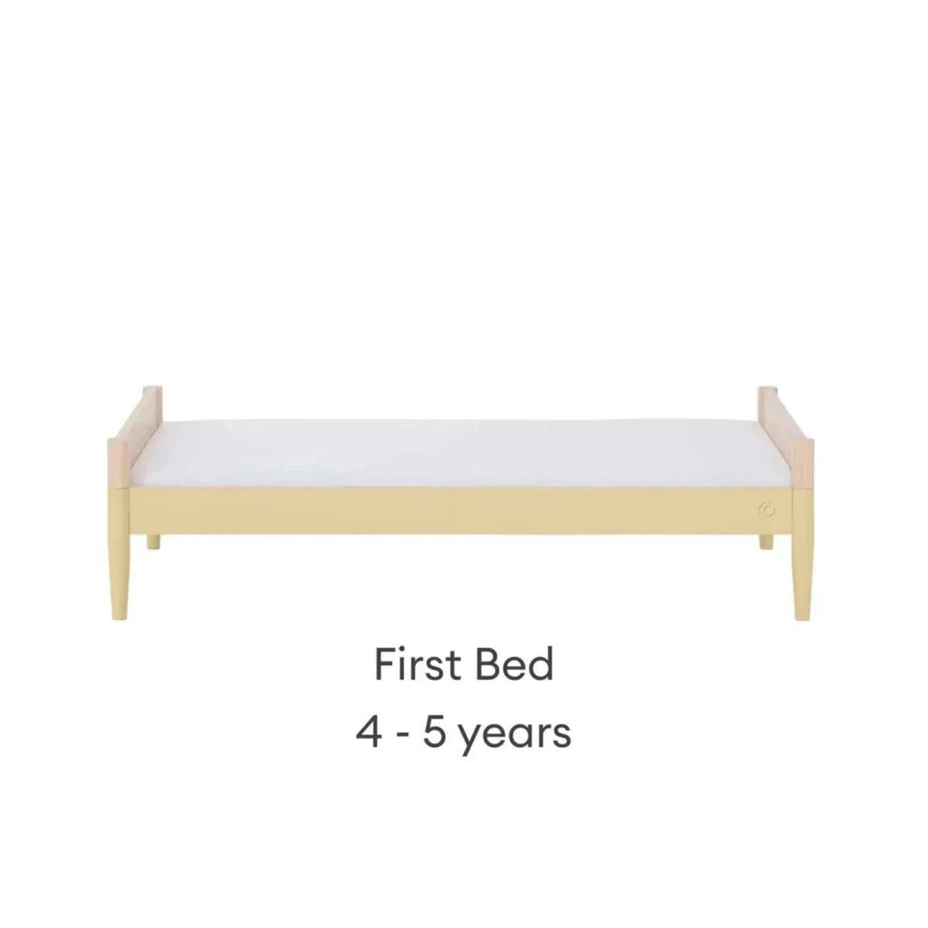 Convertible first bed with light wood frame and white mattress panel
