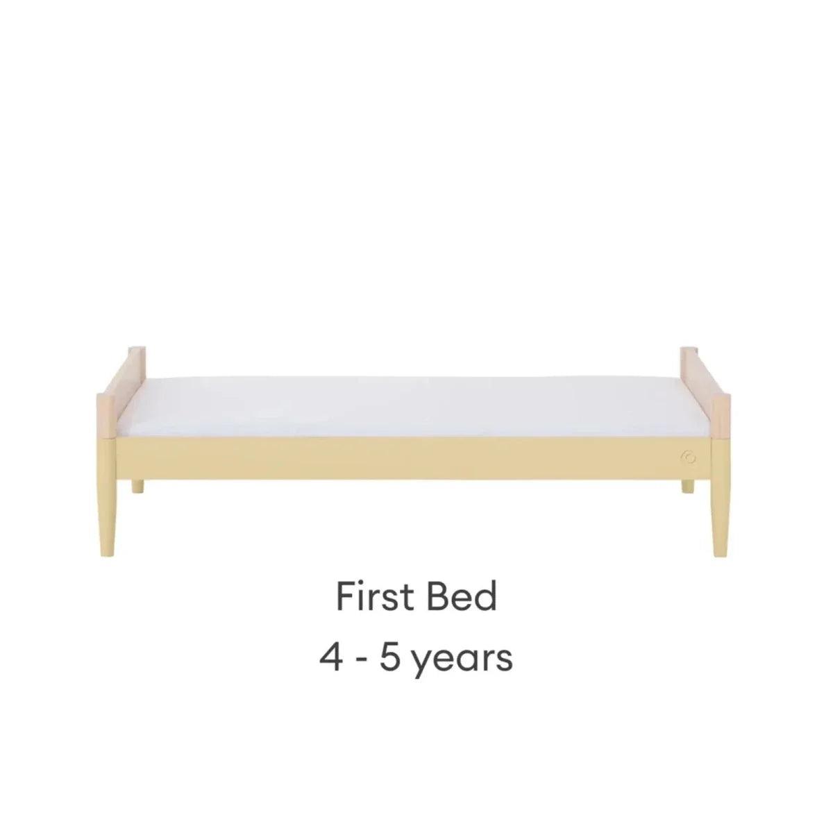 Convertible first bed with light wood frame and white mattress panel