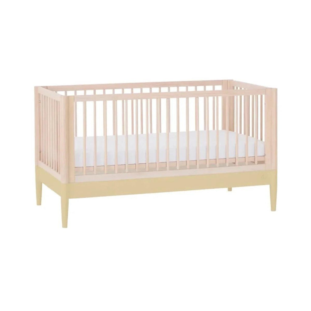 Baby crib with slatted sides, light wood frame, and pale yellow legs