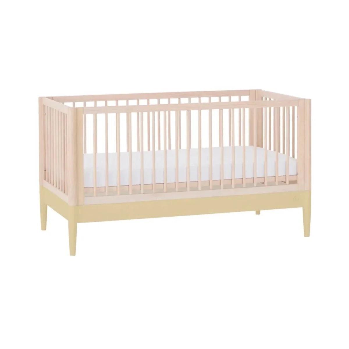 Baby crib with slatted sides, light wood frame, and pale yellow legs