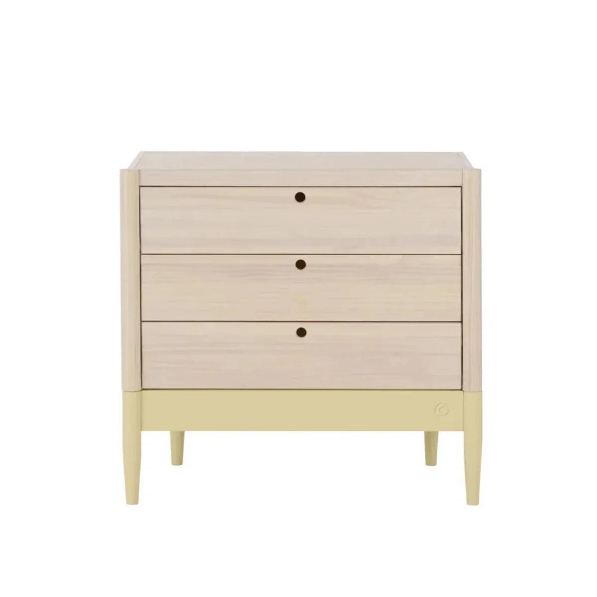 Wood baby dresser with three drawers and centered round knobs, pale yellow lower panel