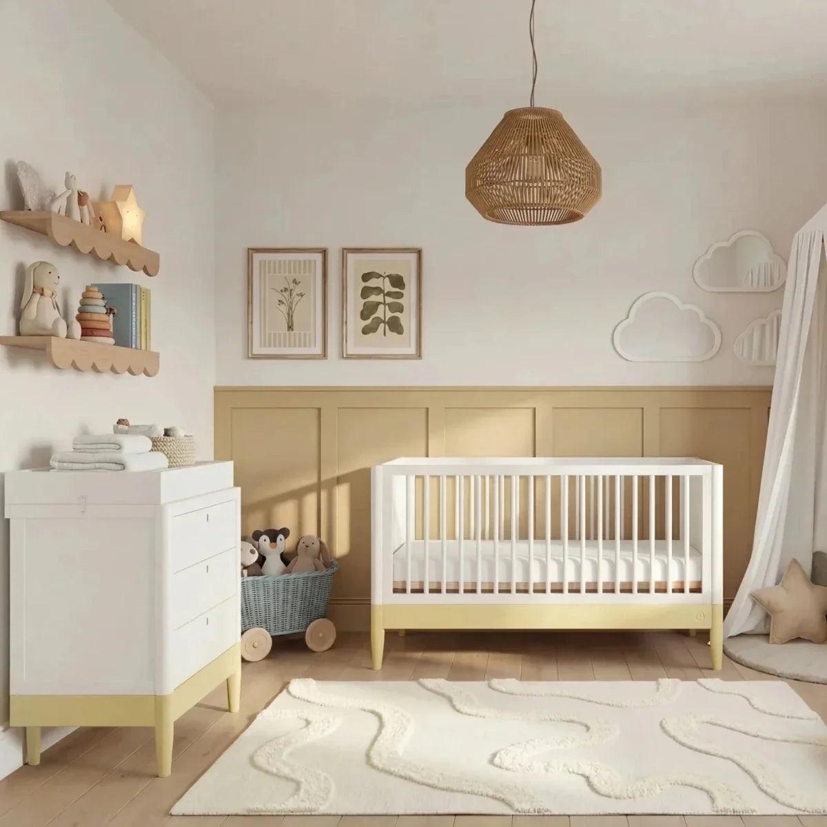 White baby cot bed with primrose yellow rail and light bedding