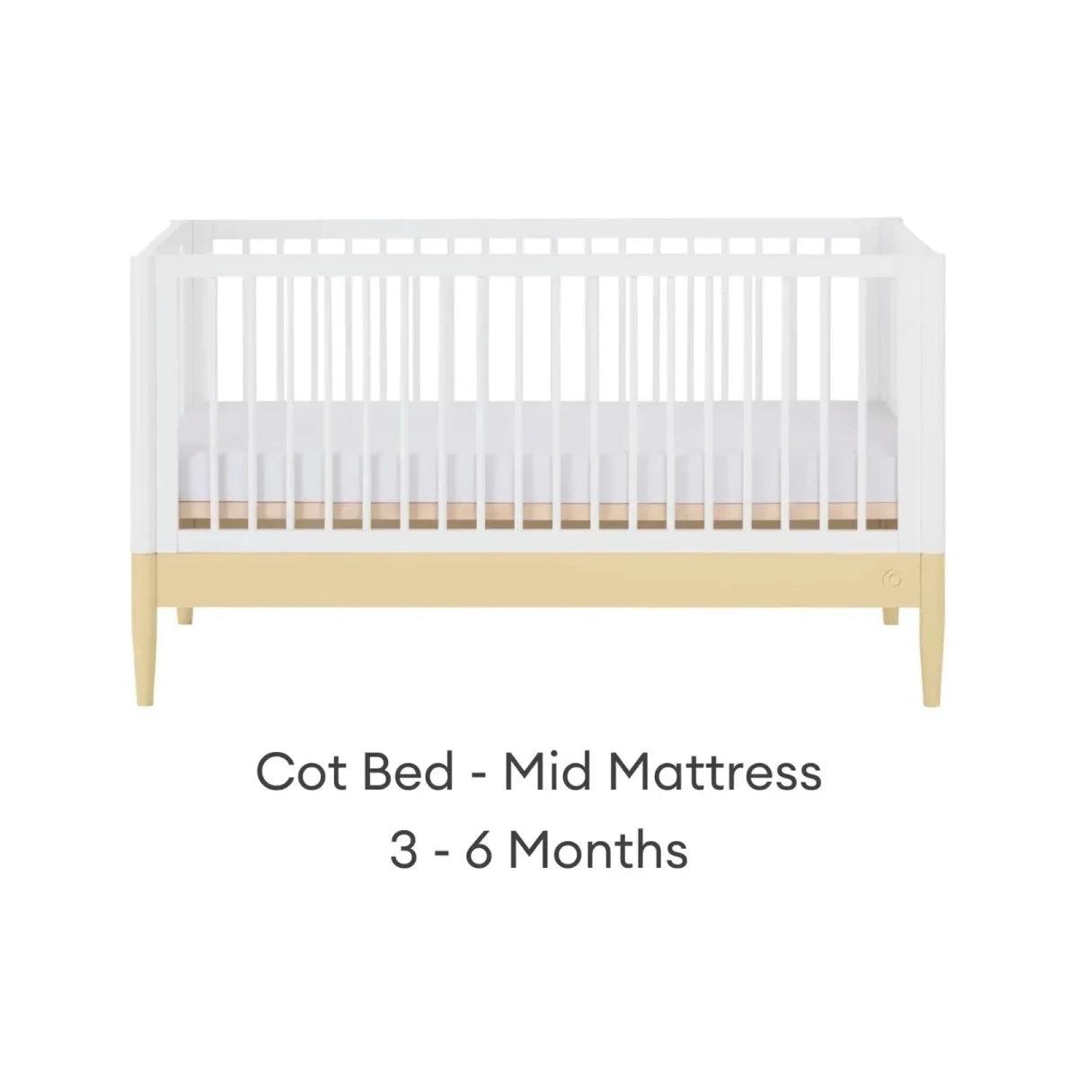 White cot bed with primrose yellow base rail and mid mattress position