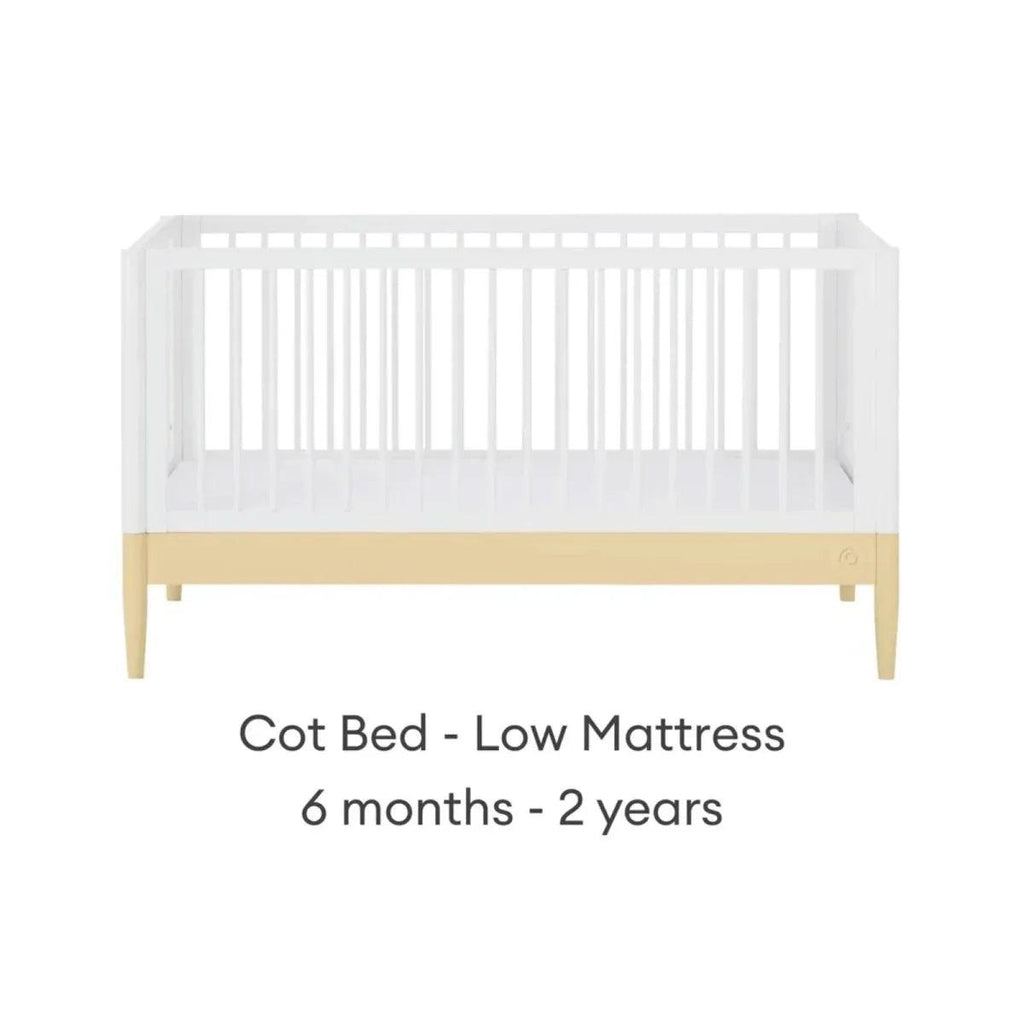 White cot bed with primrose yellow base rail and low mattress position