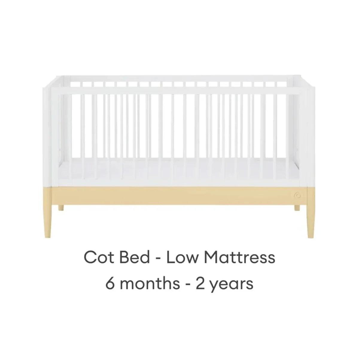 White cot bed with primrose yellow base rail and low mattress position