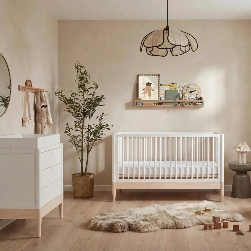White and natural baby cot bed with vertical slats and low guard rails