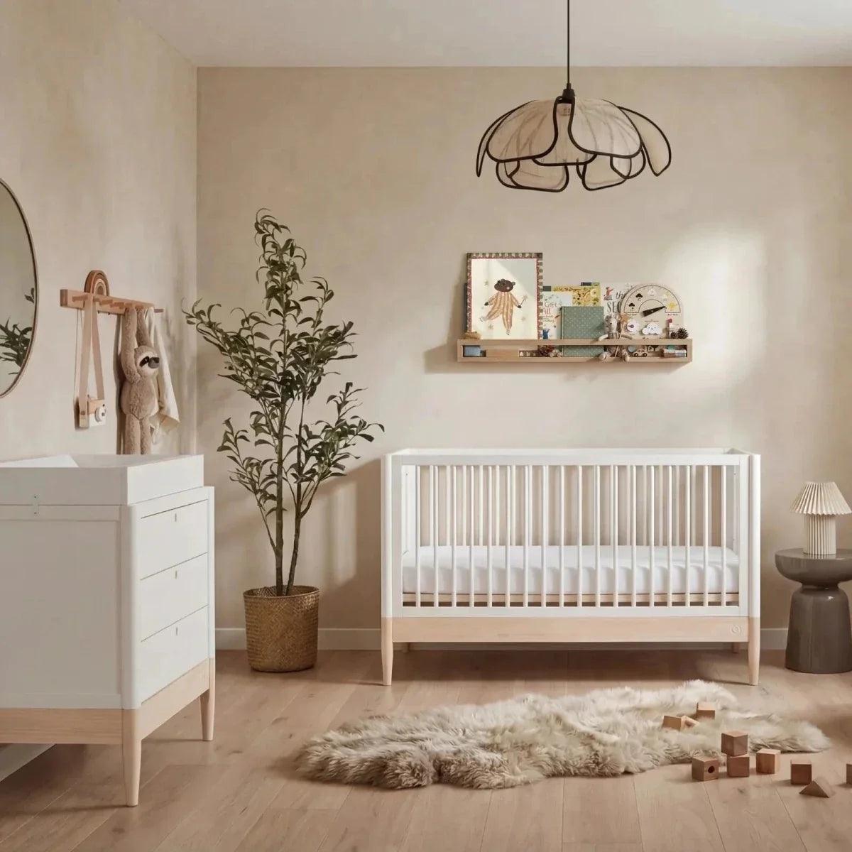 White and natural baby cot bed with vertical slats and low guard rails