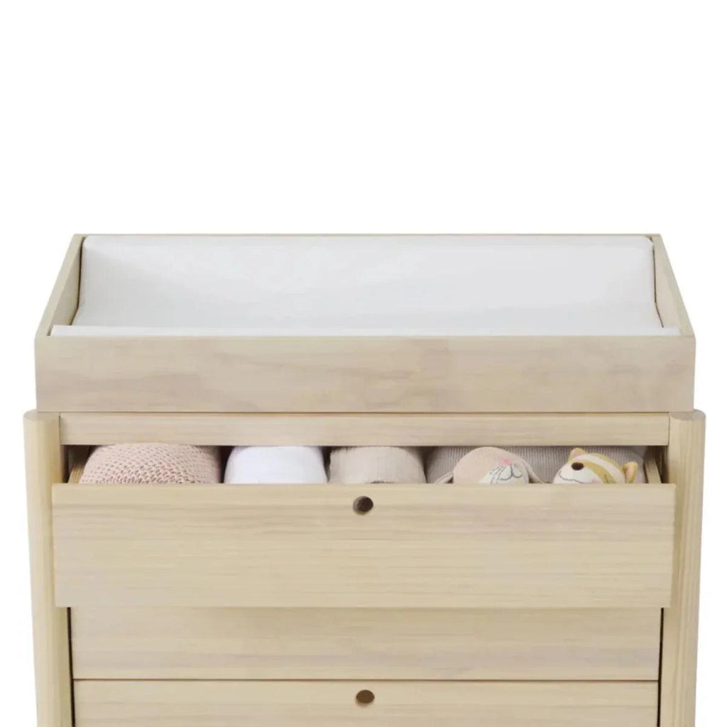Baby changing chest with open storage drawer showing changing pad and small toys