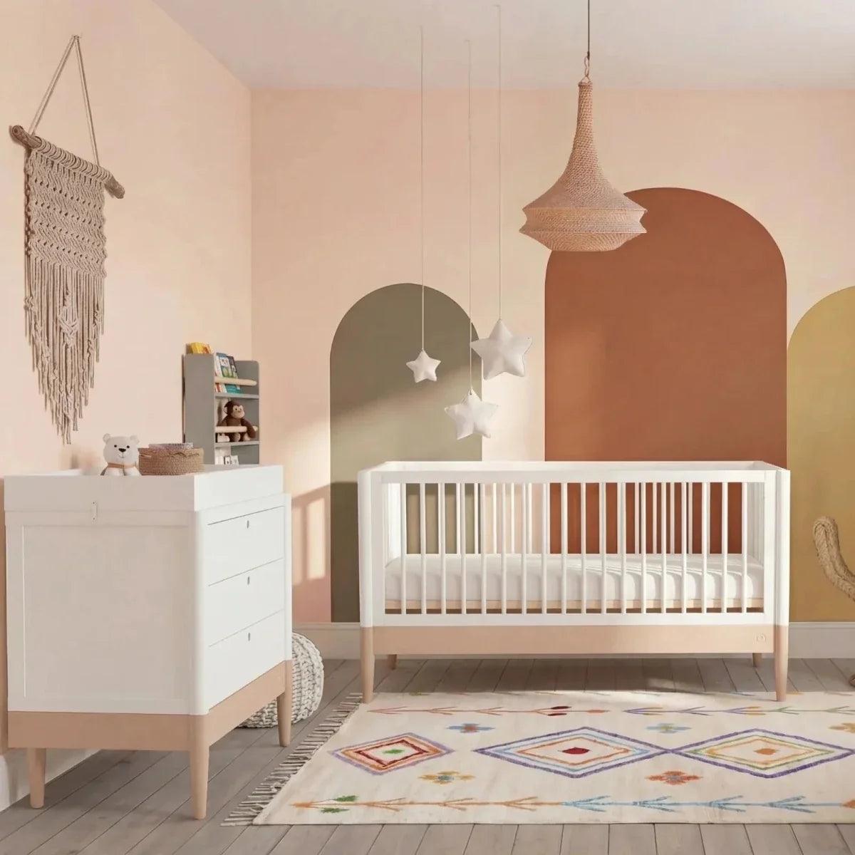 Powder blush and white baby room set with white crib in nursery scene