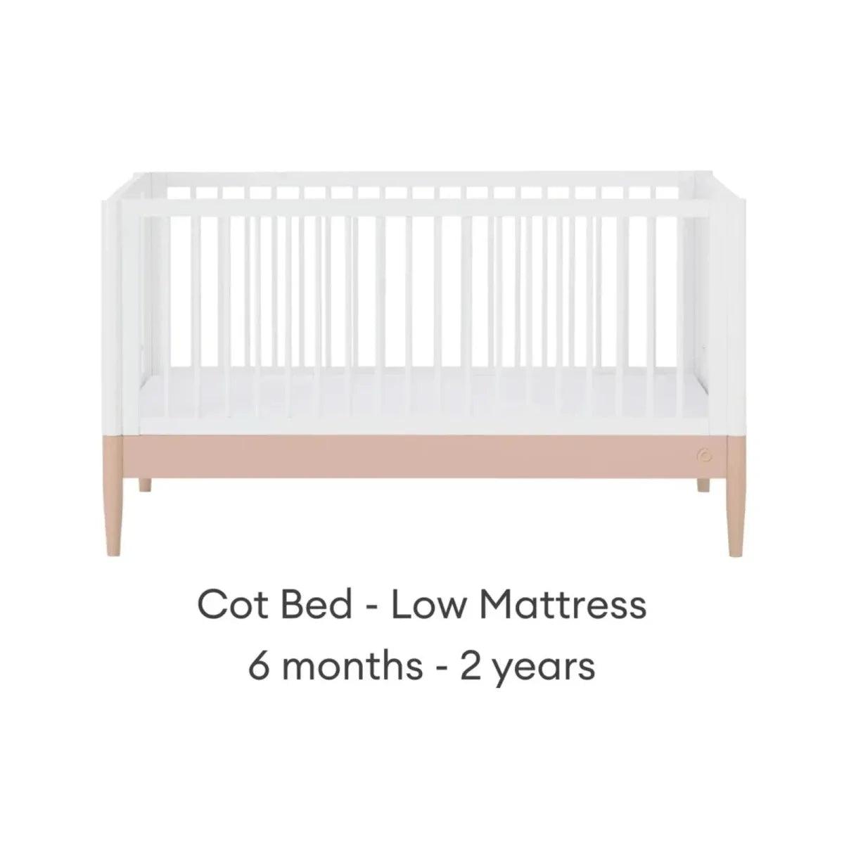 White cot bed with blush mattress band in low position