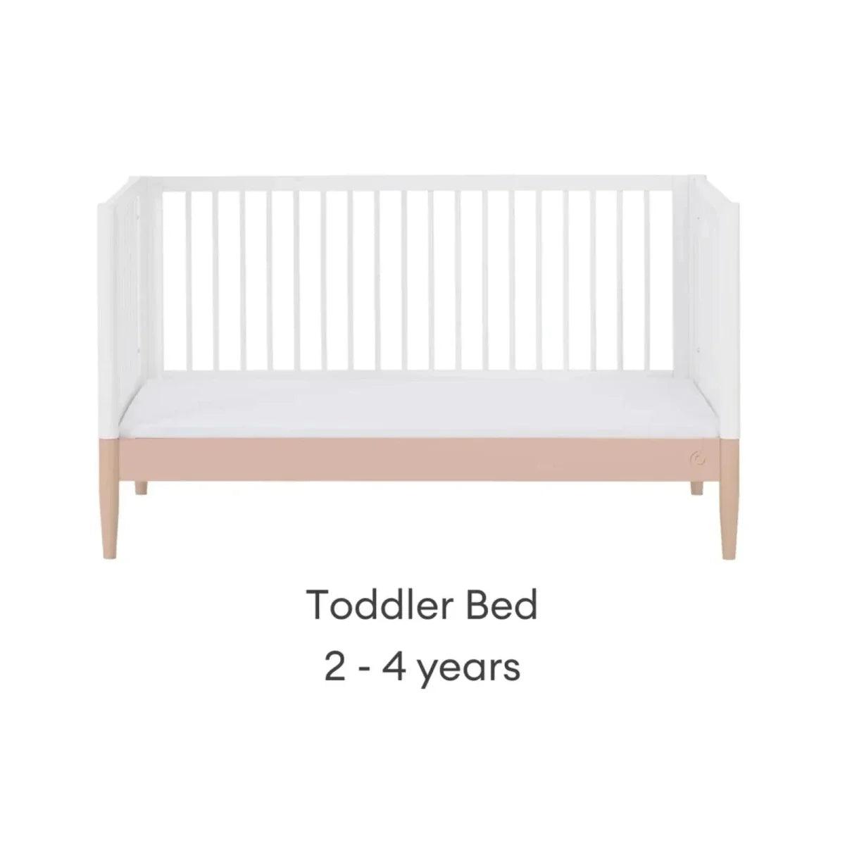 White toddler bed with blush mattress band