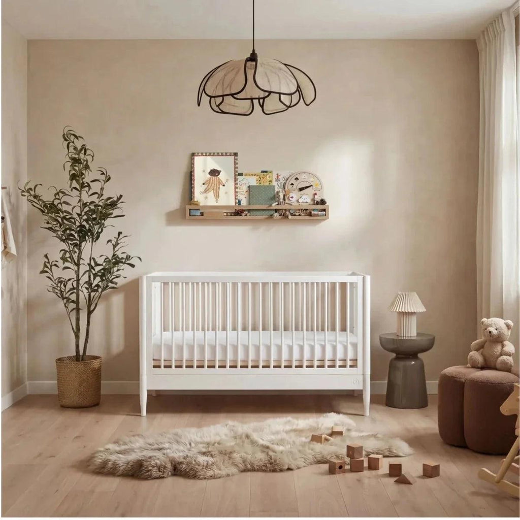 White nursery cot bed with vertical slat sides and rounded legs