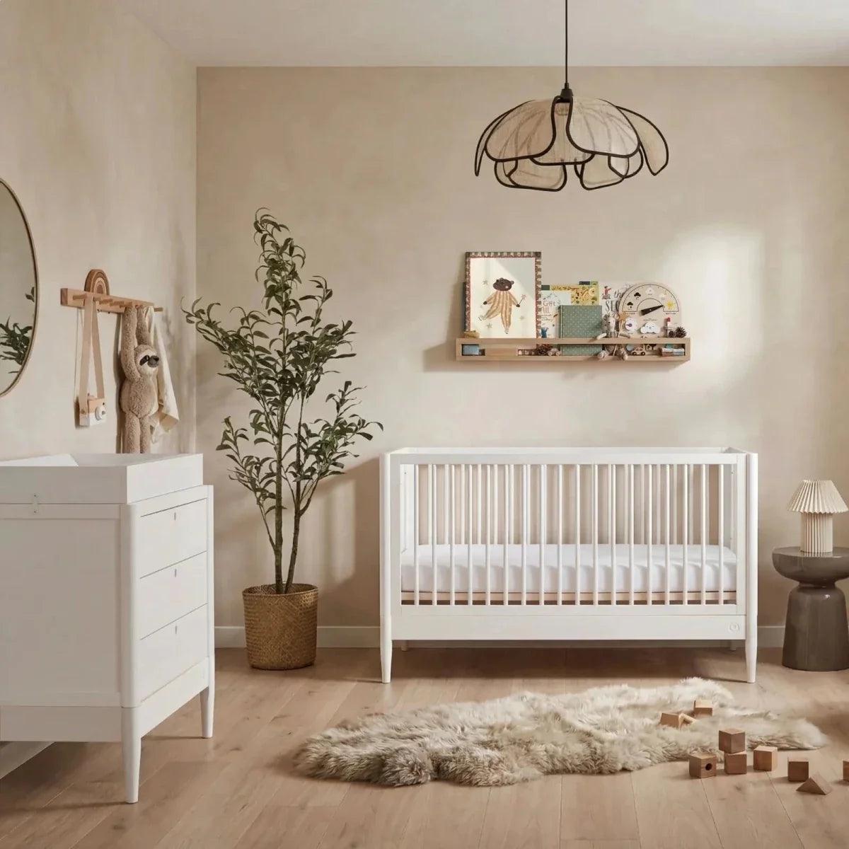 White nursery cot bed with slatted guard rails and arched end posts
