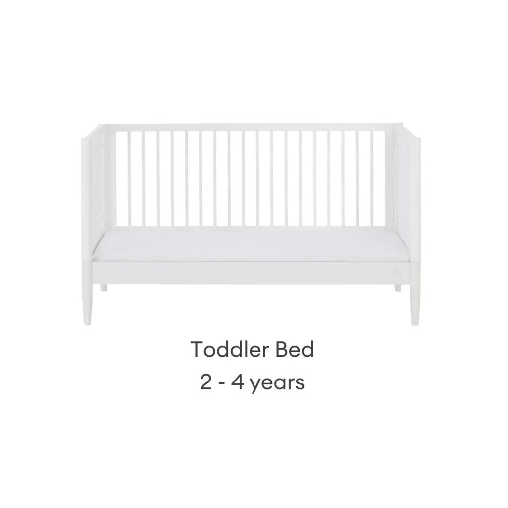 White toddler bed with low rail and vertical slat headboard