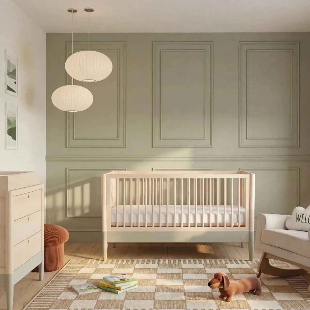 Baby cot bed with vertical slat railing, natural wood frame and desert sage panel, nursery