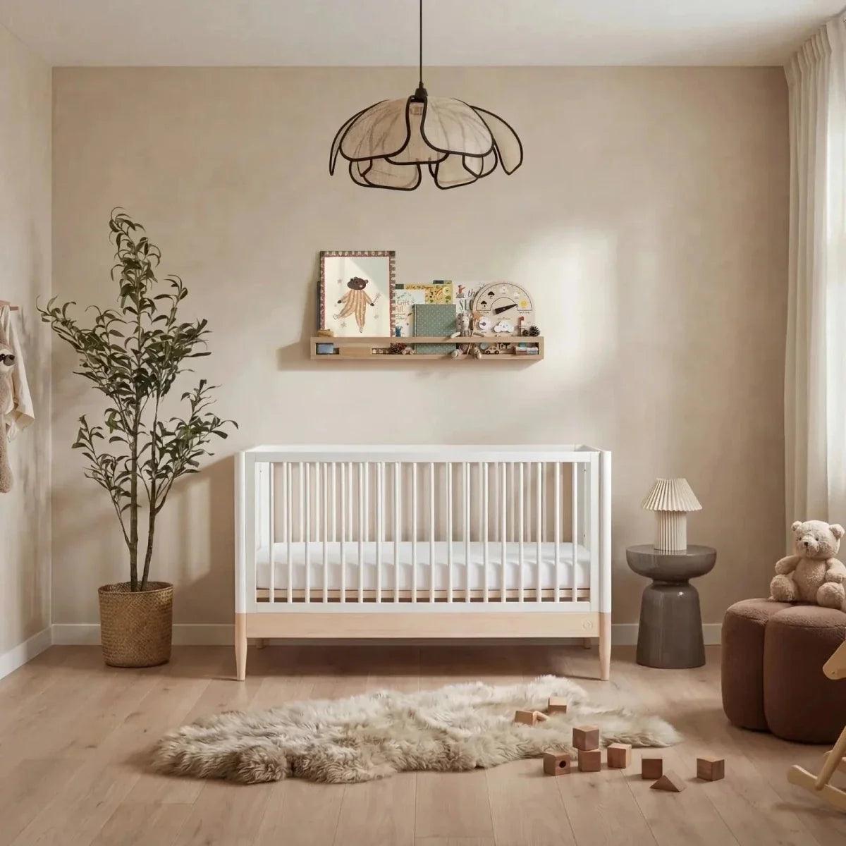 Natural ash and white baby cot bed with vertical slat rails and sturdy legs.