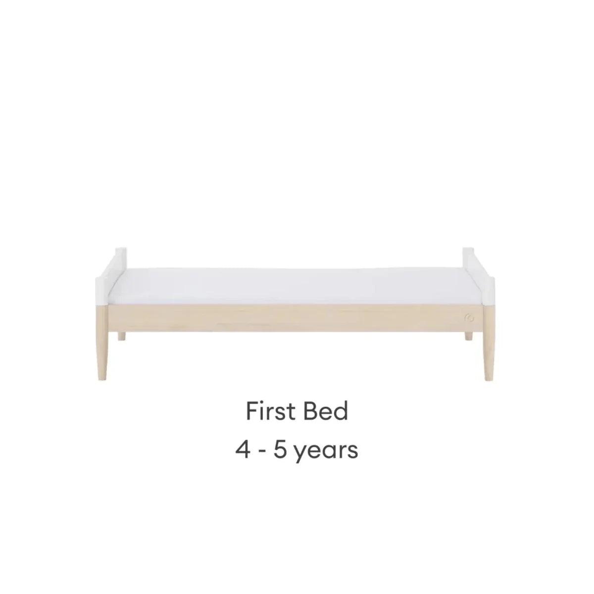 White cot bed in first bed setup with natural wood end panels and side feet.