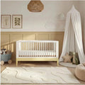 White and primrose yellow nursery cot bed with slatted rails and light wood legs