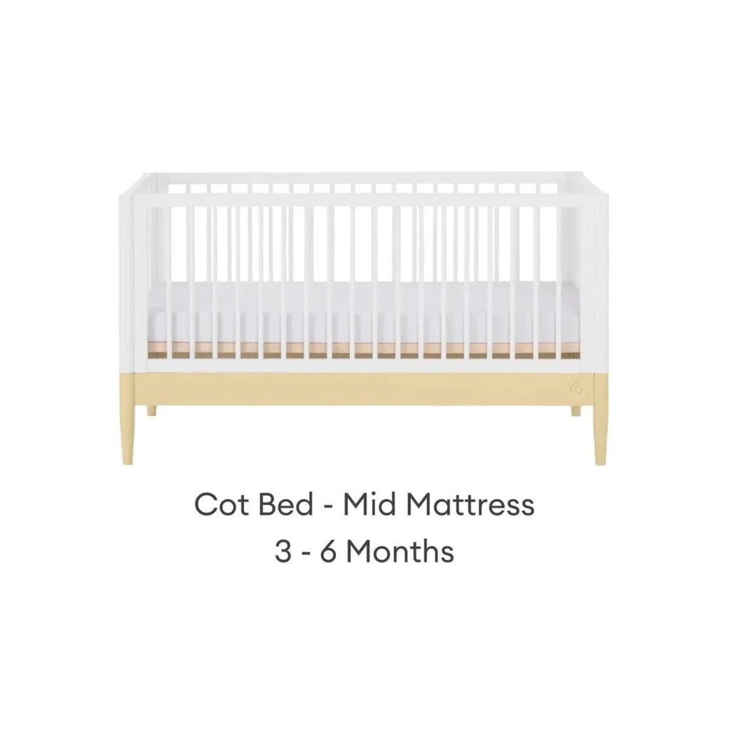 Cot bed with white slatted sides and primrose yellow rail, pale wood legs