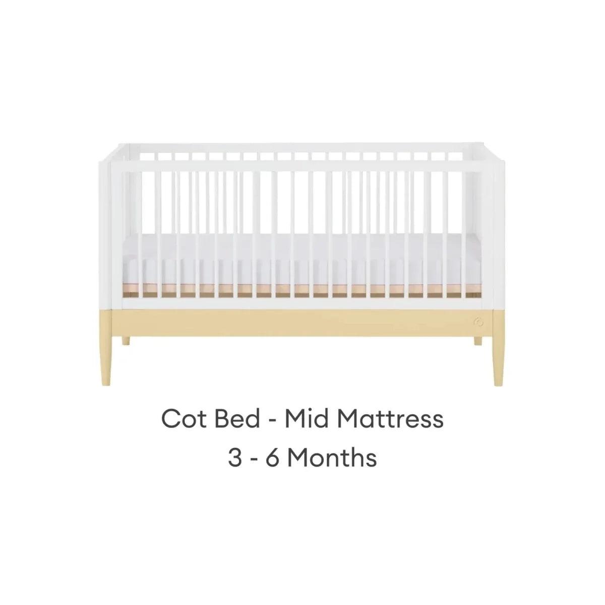 Cot bed with white slatted sides and primrose yellow rail, pale wood legs