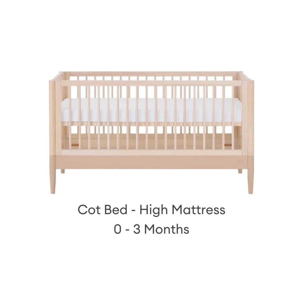 Cot bed with high mattress position, natural ash frame and vertical slatted rails.