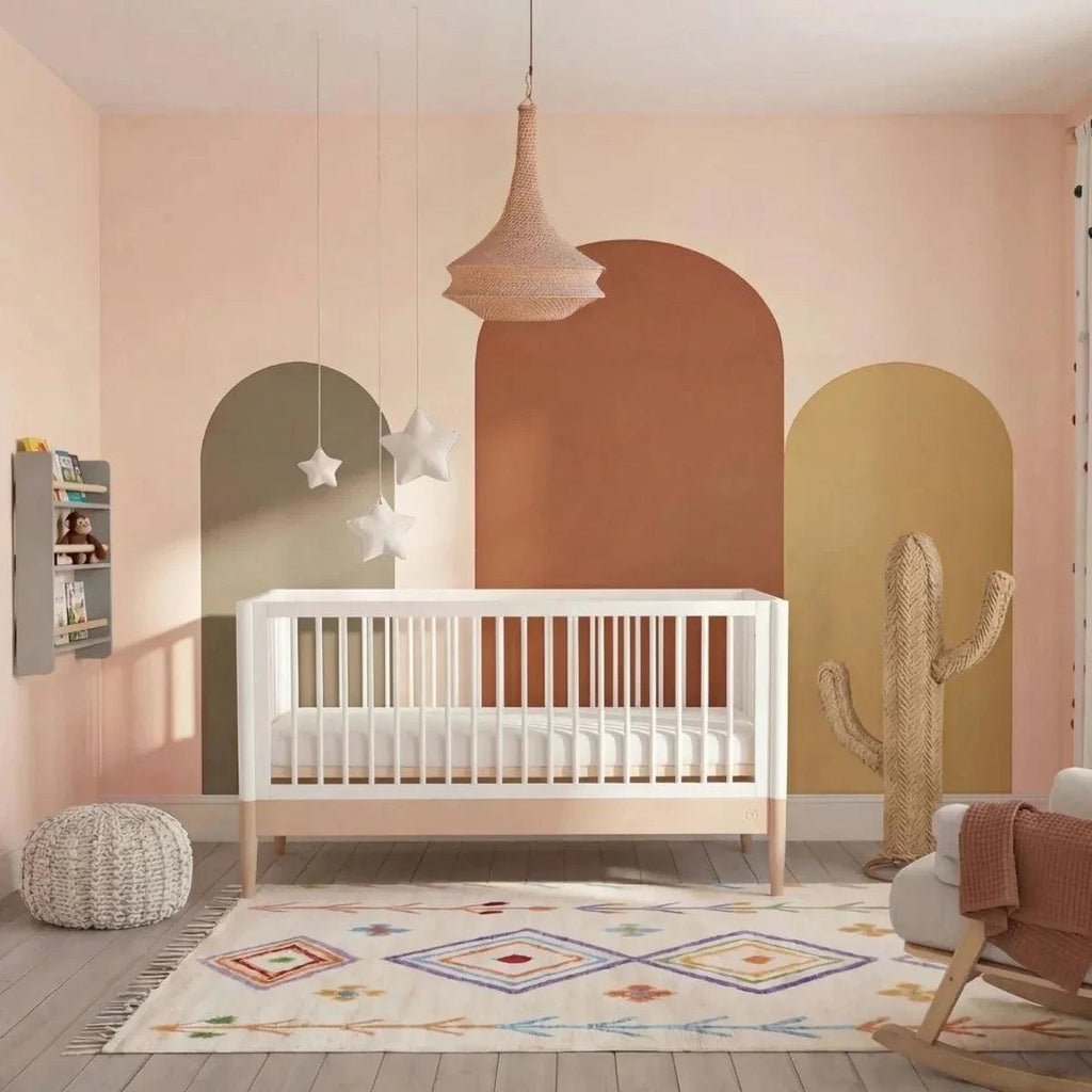 Powder blush and white nursery cot bed with vertical slats and arched end panels