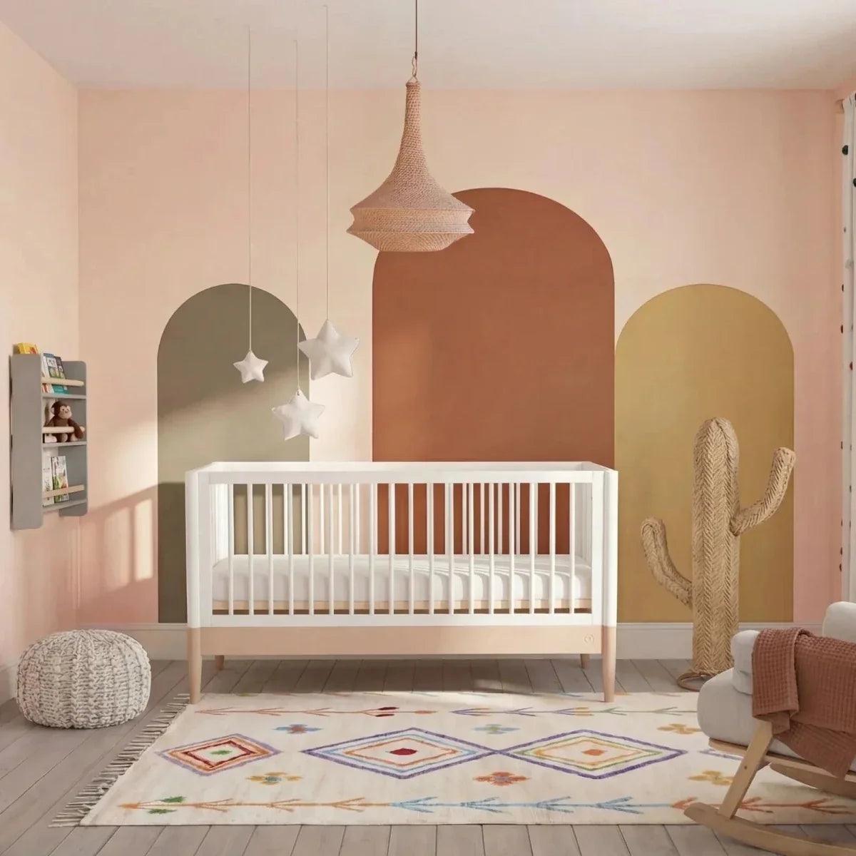 Powder blush and white nursery cot bed with vertical slats and arched end panels