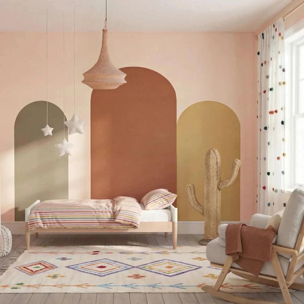 White nursery cot bed with powder blush side rail and open vertical slat design
