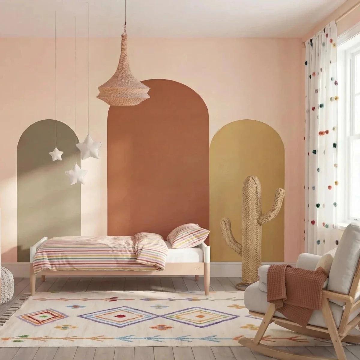 White nursery cot bed with powder blush side rail and open vertical slat design