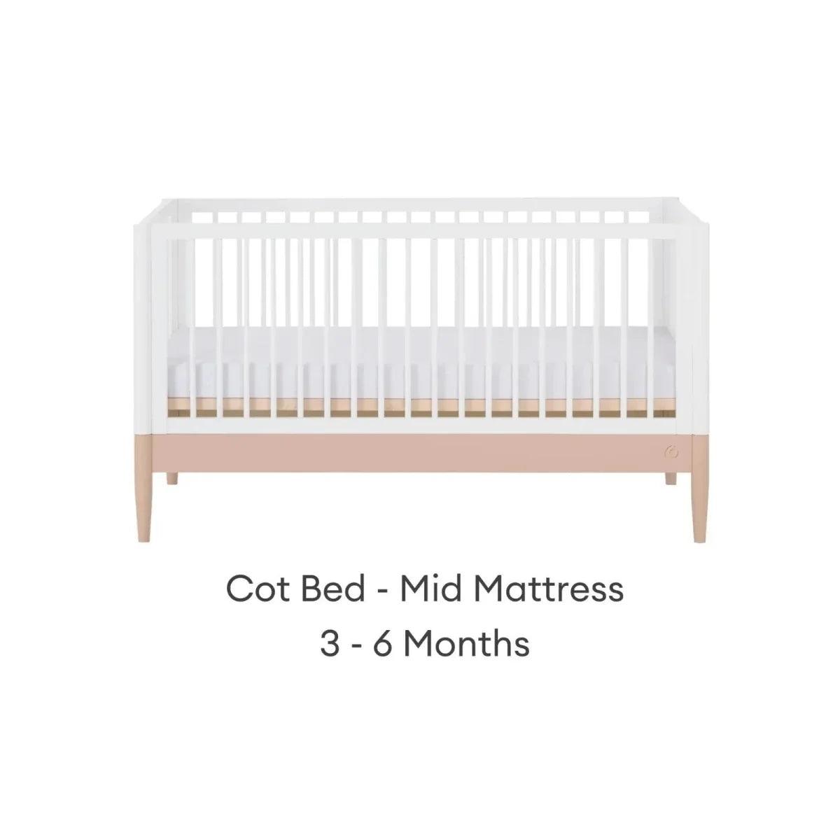 White cot bed with powder blush rail and vertical slats, mid mattress position