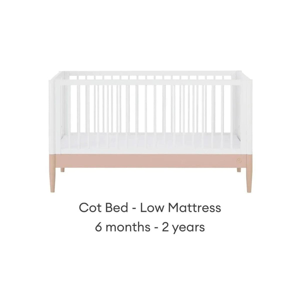 White cot bed with powder blush rail and vertical slats, low mattress position
