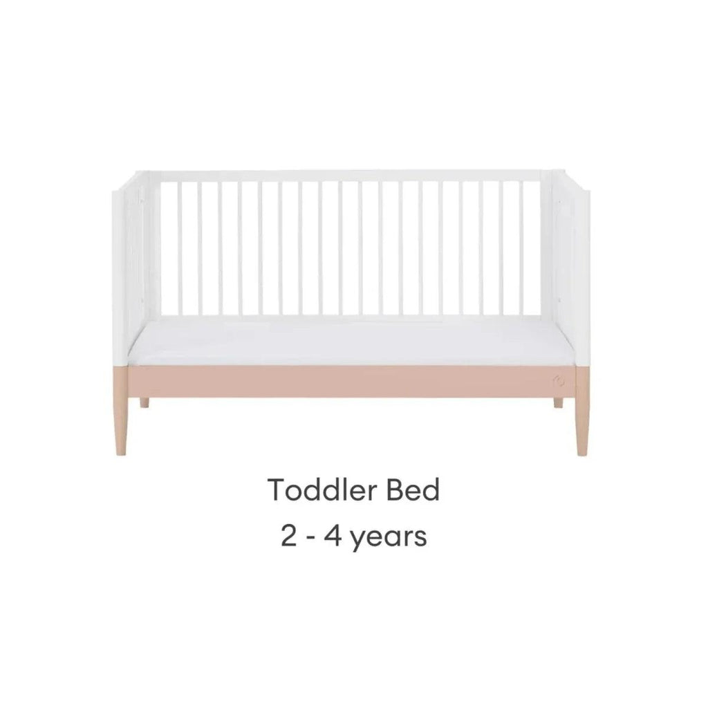 White toddler bed with powder blush rail and vertical slat headboard
